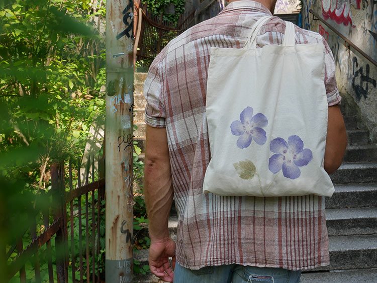 De stoffen tas die een man over zijn schouder draagt, is versierd met bloemenafdruk.