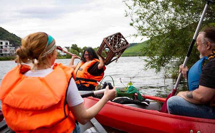 Freiwillige sammeln in Booten beim Clean-Up Müll aus dem Fluss heraus.